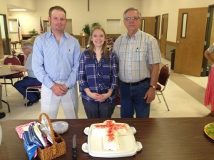 Cole Hegeman, Amelia Hegeman and Don Trajacek pose before cutting the cake at a reception for them after joining the church.
