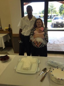 Keith, Nicole, and Ariana pose in front of the special cake to celebrate the baptisms.