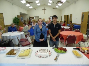 Amanda Jurek and Toby Brzozowski preparing to cut their special Graduate Recognition cake at the reception for them in the Fellowship Hall.