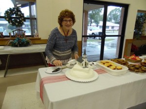 Peggy Spitzenberger getting ready to cut the special Marker Dedication celebration cake during the brunch held after the program.  A replica of the old church built in 1901 rests on top of the cake.