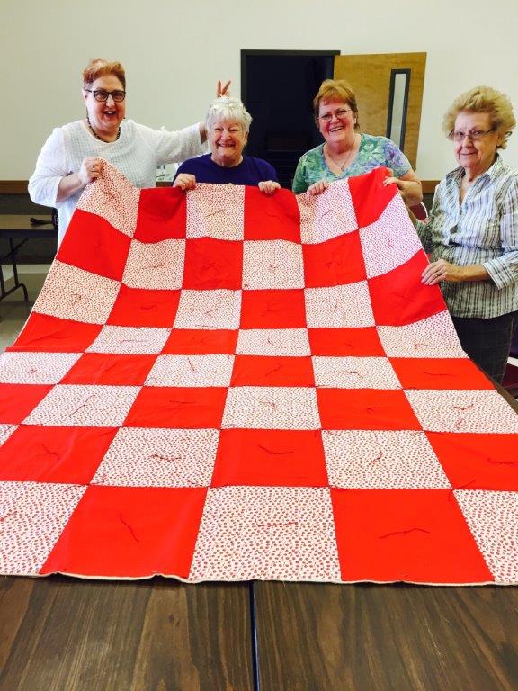 LWML members Judy Stallings, Sheila Johnson, Maxine Cates, and Annie Mae Korenek display one of many quilts they are making for Lutheran World Relief.